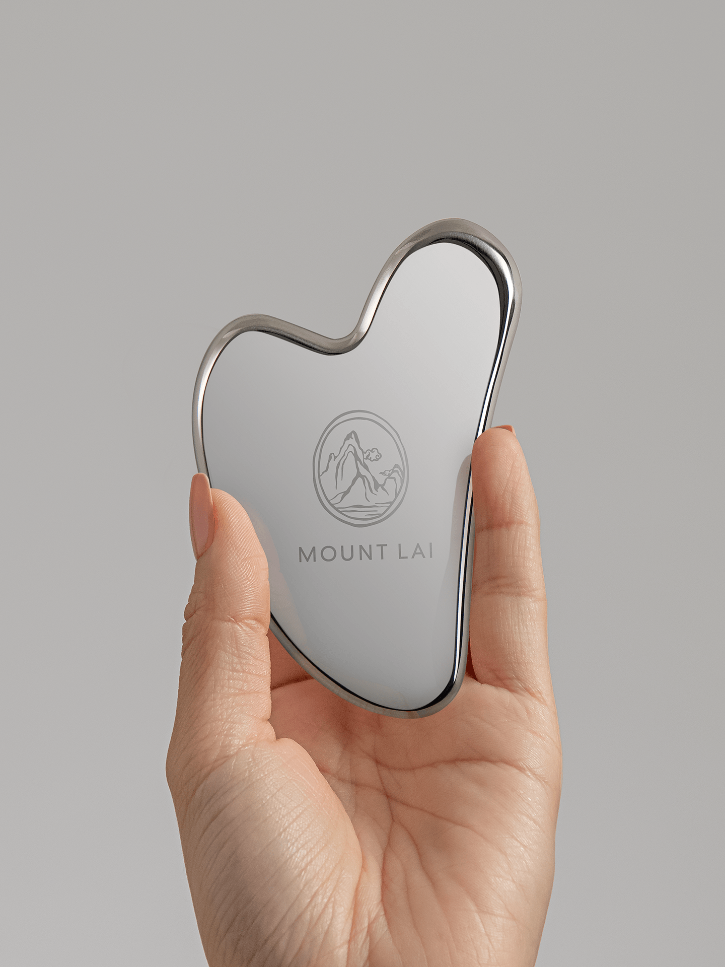 Hand holding up award winning stainless steel gua sha lifting tool