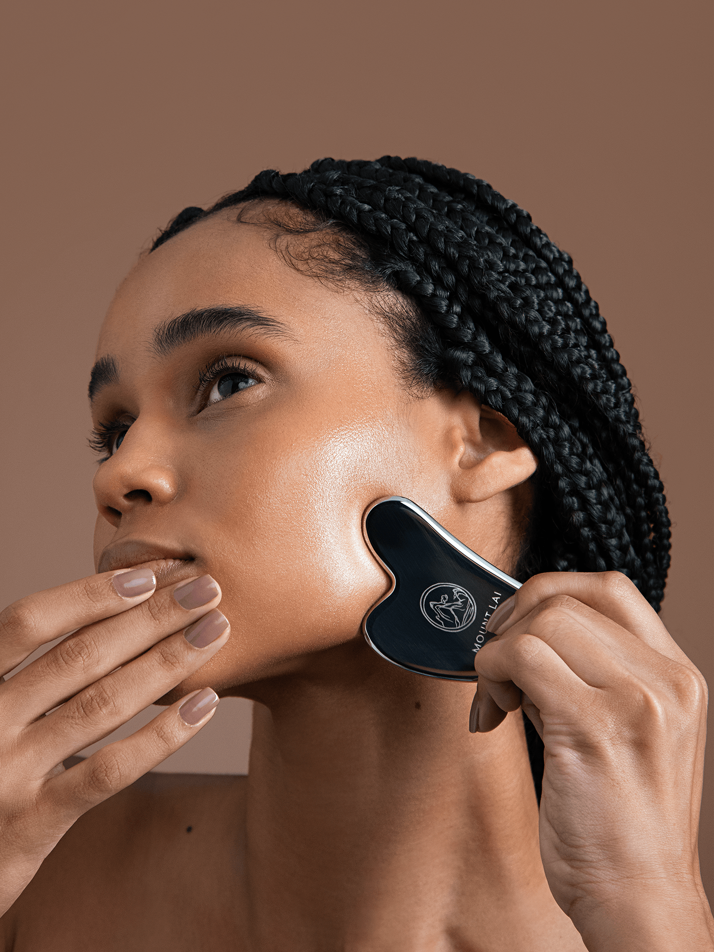 Woman using stainless steel gua sha lifting tool to sculpt jawline