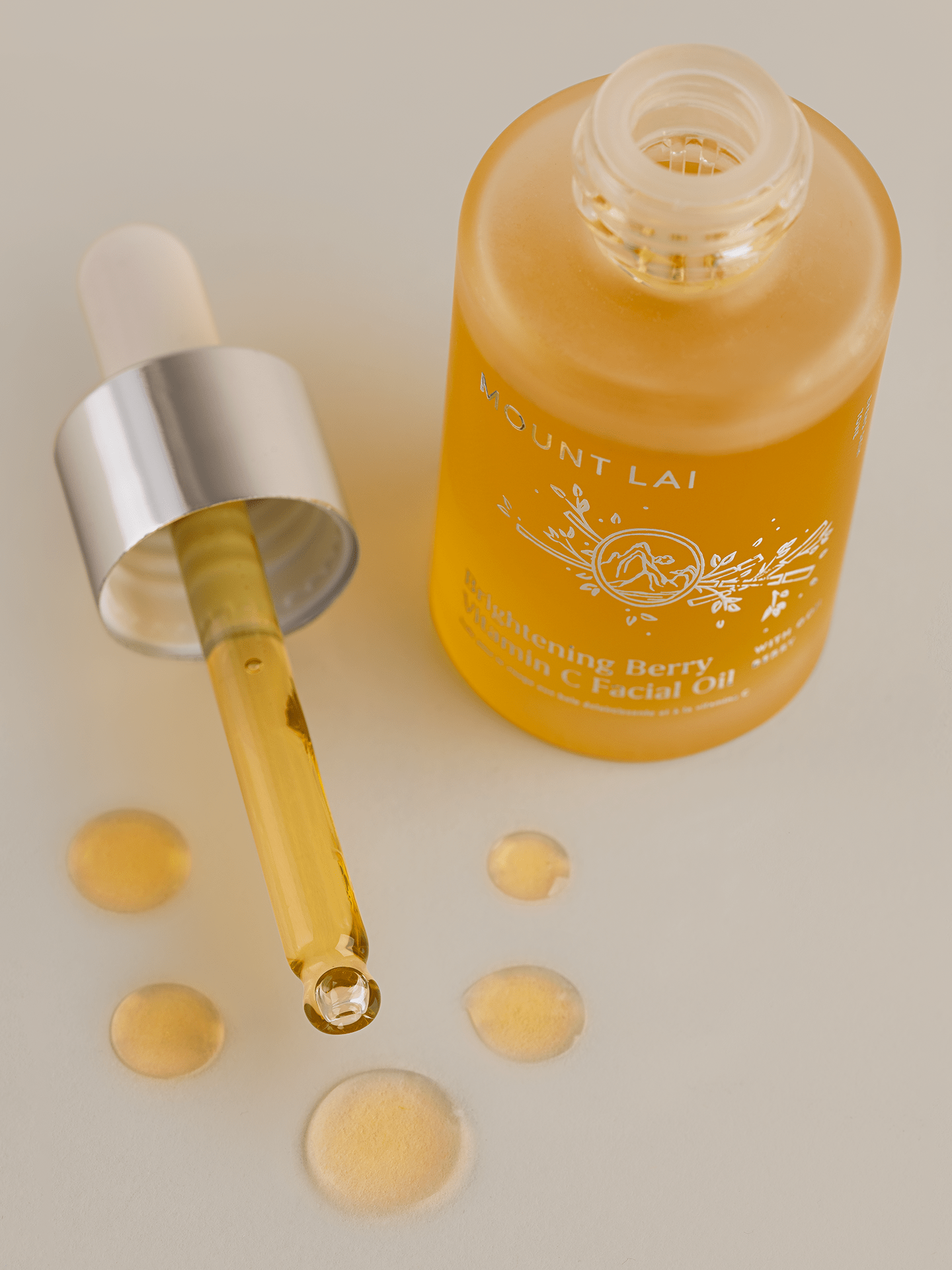 Droplets next to bottle of brightening berry vitamin c facial oil 